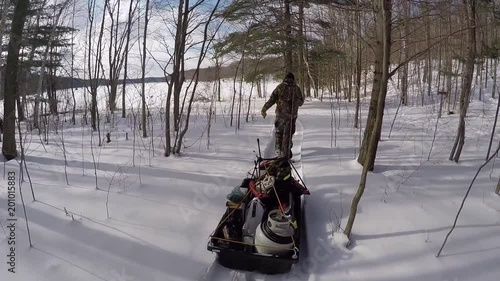 man towing camping gear through the winter forest trail photo