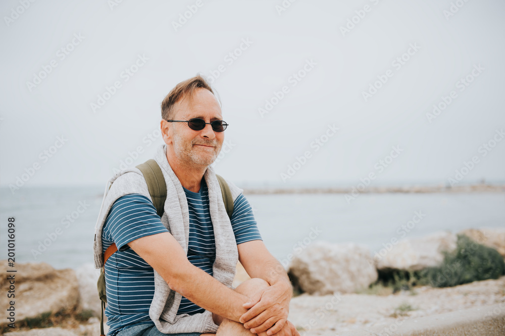 Man enjoying summer vacation by the sea, wearing stripe nautical t-shirt and backpack. Image taken in Saintes-Maries-de-la-Mer, capital of Camargue, south of France