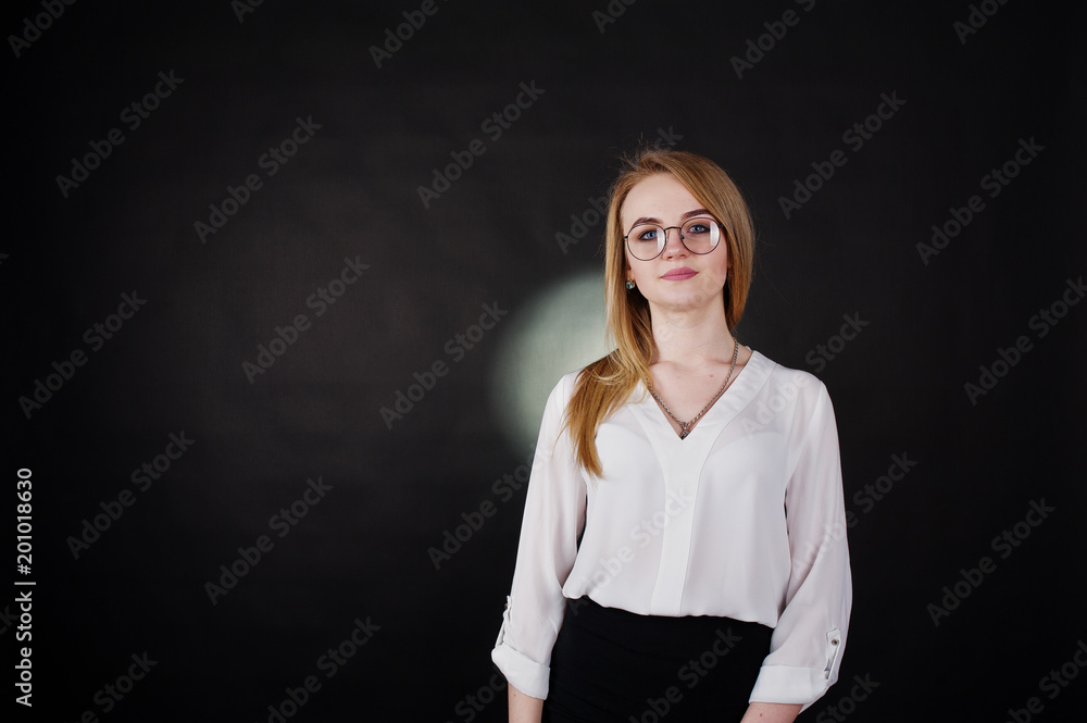 Studio portrait of blonde businesswoman in glasses, white blouse and black skirt against dark background. Successful woman and stylish girl concept. Studio portrait of blonde businesswoman in glasses, white blouse and black skirt against dark background. Successful woman and stylish girl concept.