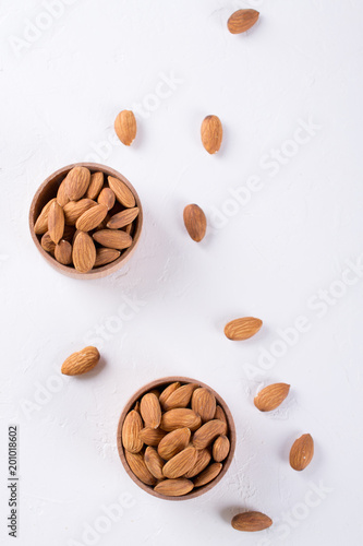 Almonds in brown wooden bowl on white background