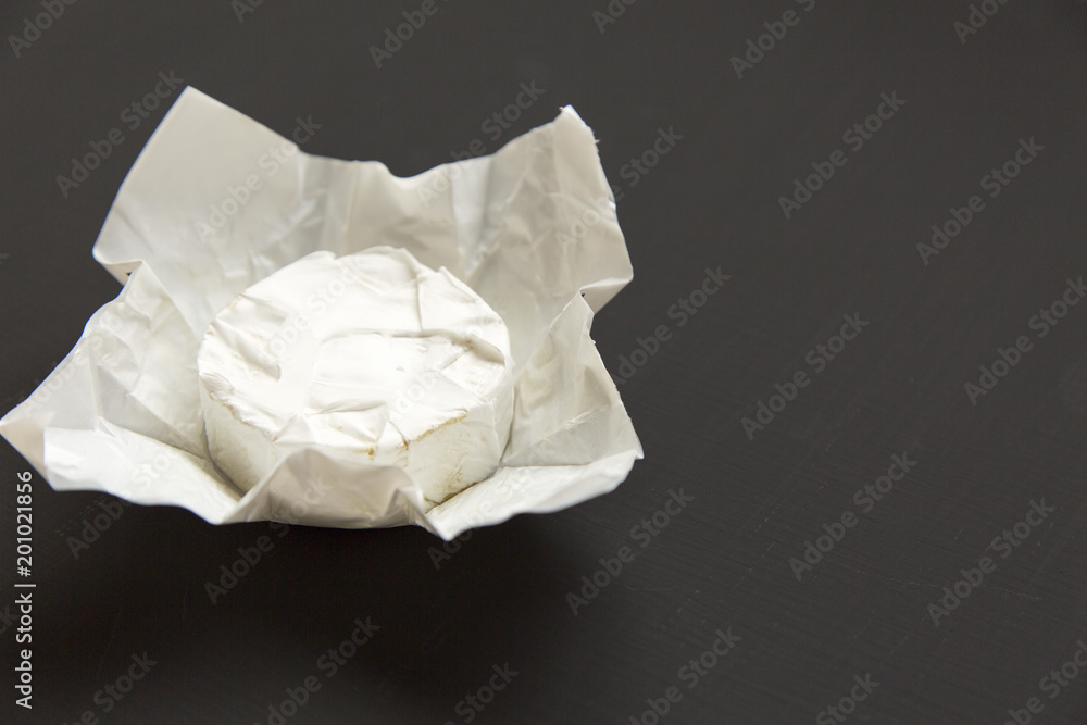 Cheese camembert or brie on dark background. Milk production. Side view. Closeup. Copy space.