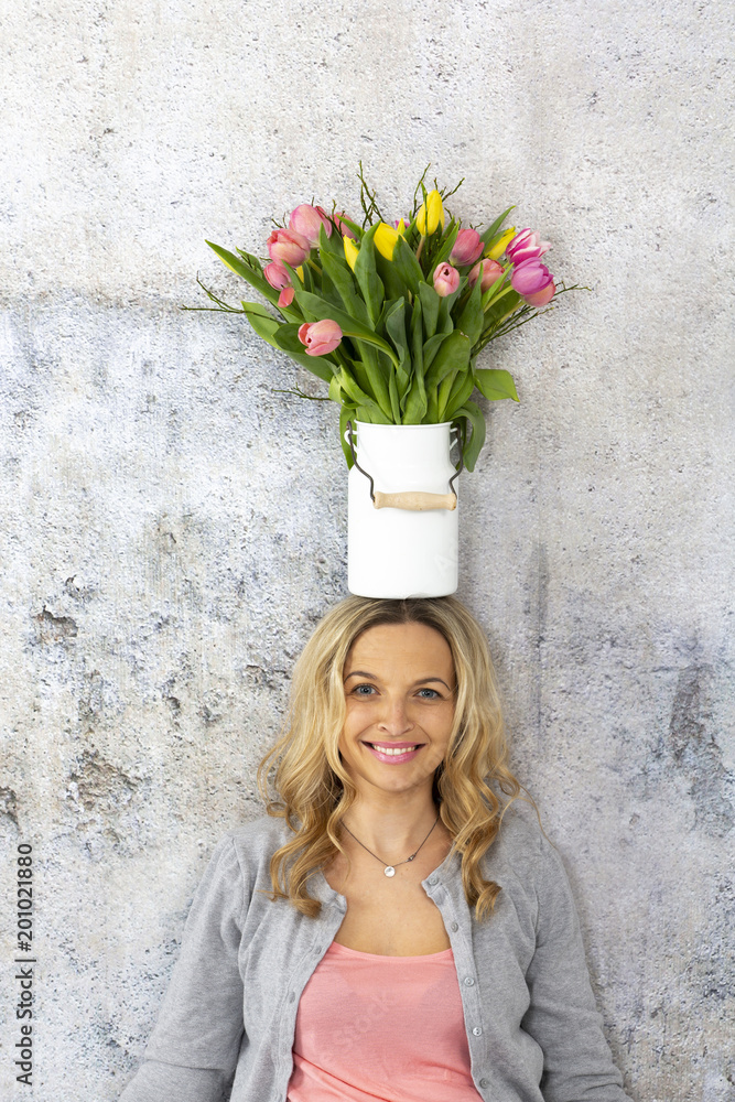 beautiful blond woman with vase full of colorful tulips