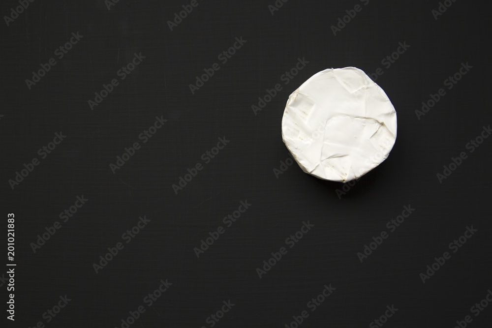 Cheese camembert or brie on dark background. Milk production. Top view. Flat lay. Copy space.
