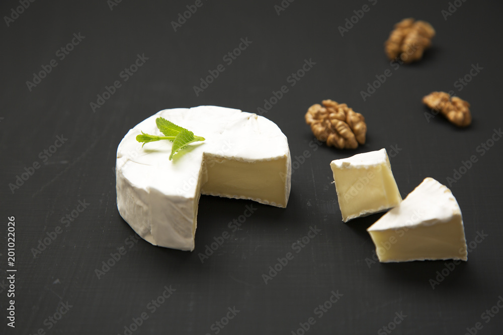 Cheese camembert or brie on dark background. Milk production. Side view. Closeup.