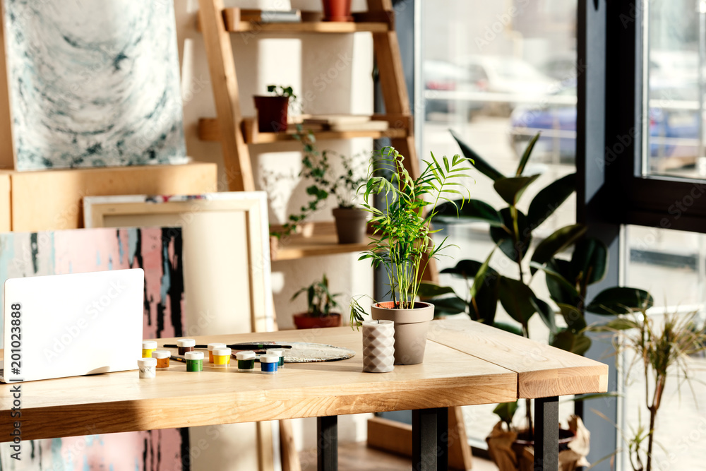 interior of artist studio with painting supplies, laptop and potted plants interior of artist studio with painting supplies, laptop and potted plants