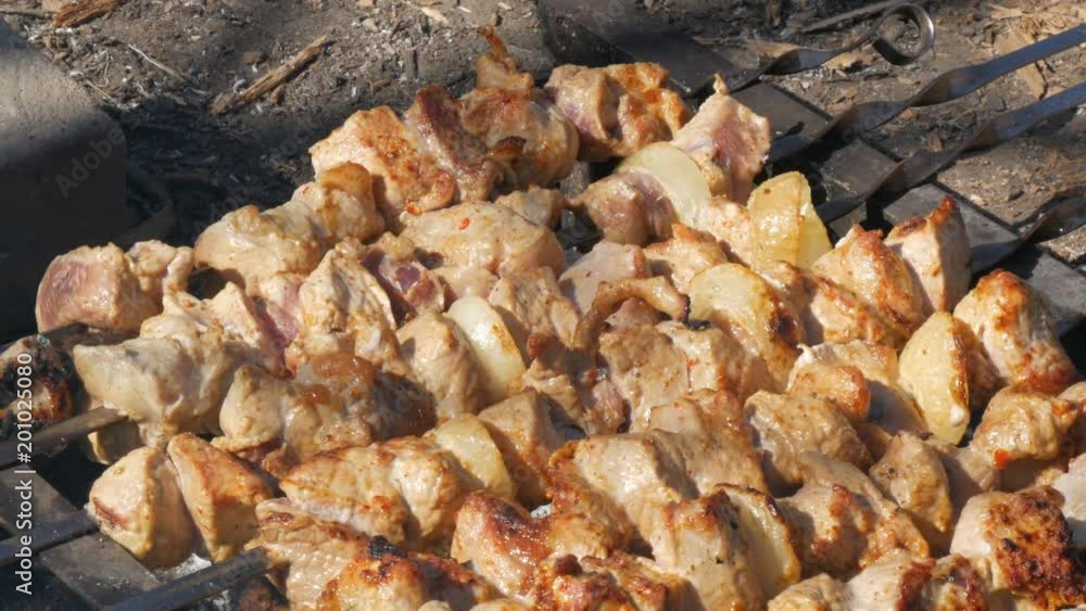 Lot of pieces of meat on skewers are roasted on a bonfire. A shish kebab or grilled meat is roasted in nature. A picnic in the countryside Lot of pieces of meat on skewers are roasted on a bonfire. A shish kebab or grilled meat is roasted in nature. A picnic in the countryside