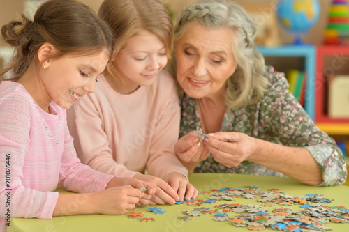 Little girls with grandmother collecting puzzles