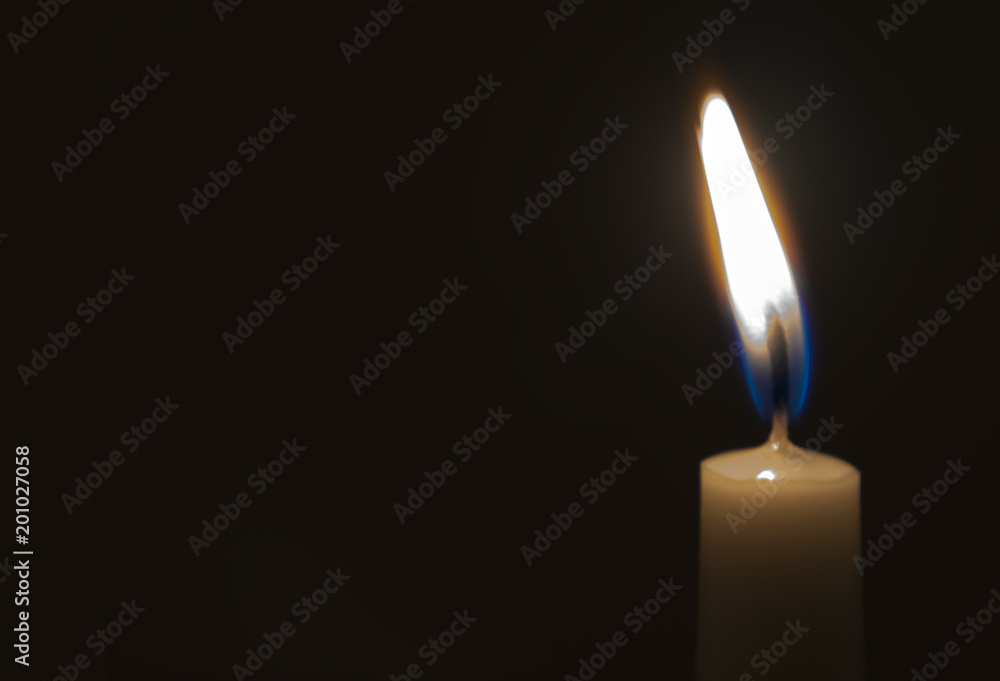One light candle burning brightly in the black background One light candle burning brightly in the black background