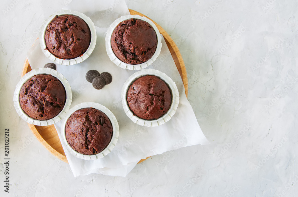 Rich chocolate zucchini muffins with chocolate chips. Close up. White stone background. Rich chocolate zucchini muffins with chocolate chips. Close up. White stone background.