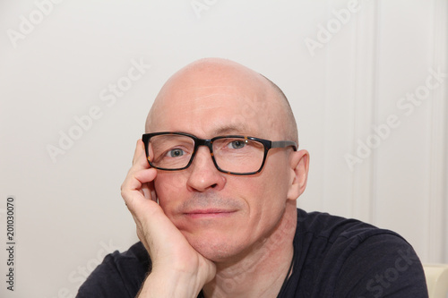 Adult bold man with crooked glasses photo