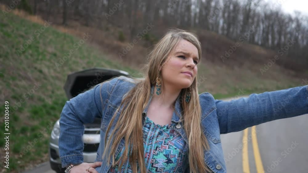 Hitchhiking woman gives a thumbs up to the camera ALT Hitchhiking woman gives a thumbs up to the camera ALT