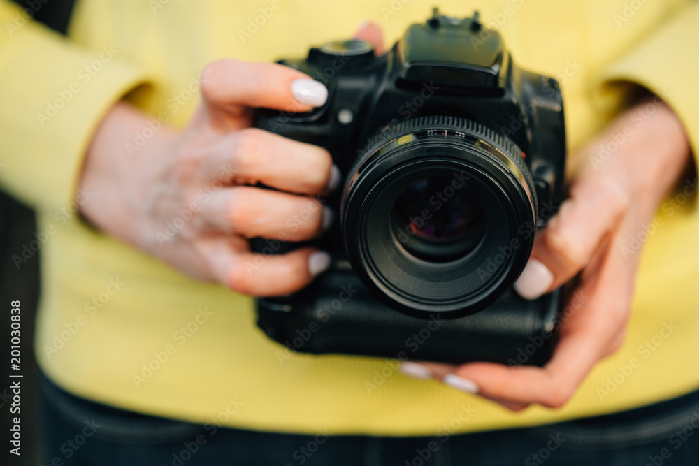 Girl with professional camera in hands. Close up of female photographer.