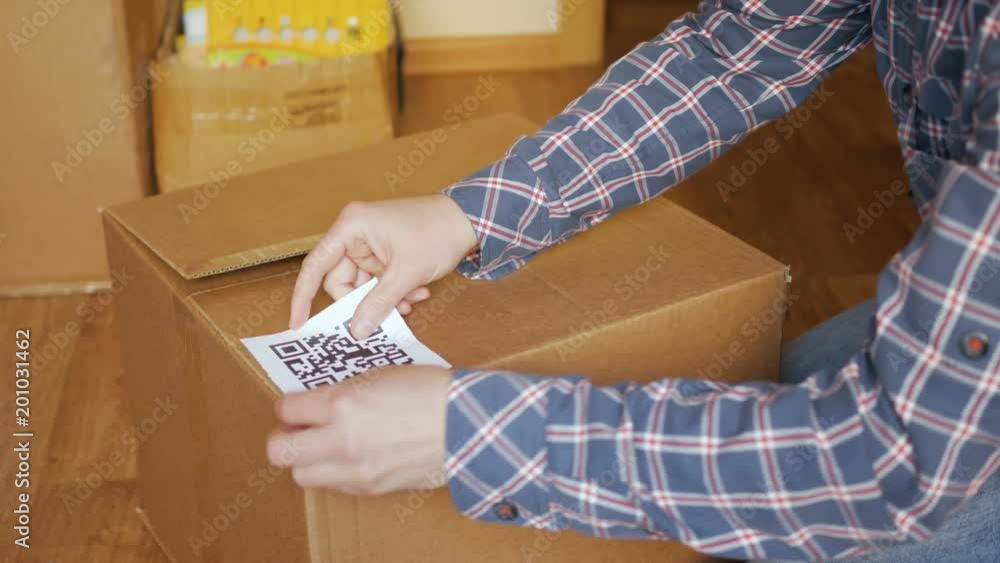 A Man Pastes A QR Code On A Box Delivery Service Online Shop Bar a-man-pastes-a-qr-code-on-a-box-delivery-service-online-shop-bar