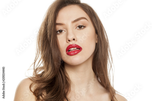 Young beautiful woman posing with red lipstick on her lips, on white background