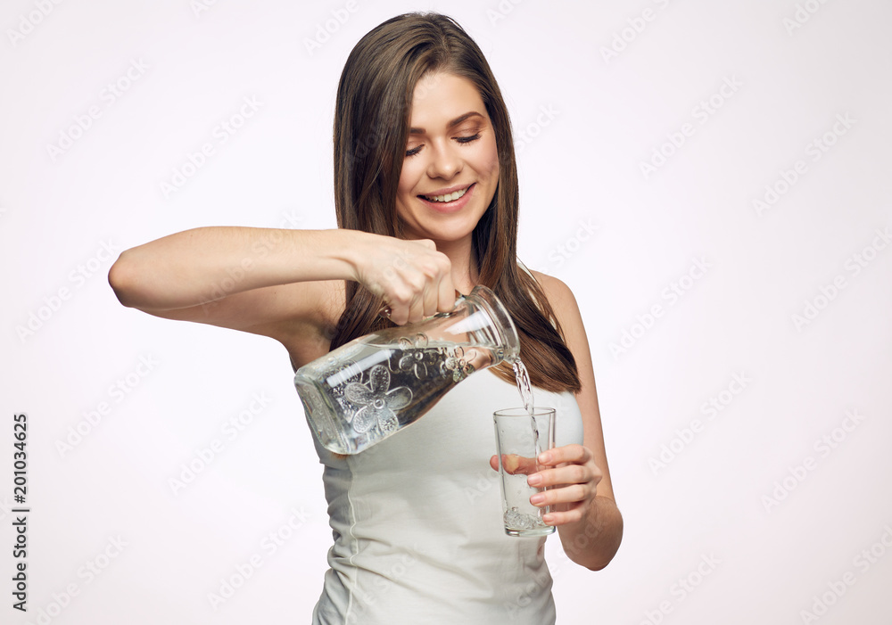 Smiling woman looking down pours water into a glass from decante Smiling woman looking down pours water into a glass from decante