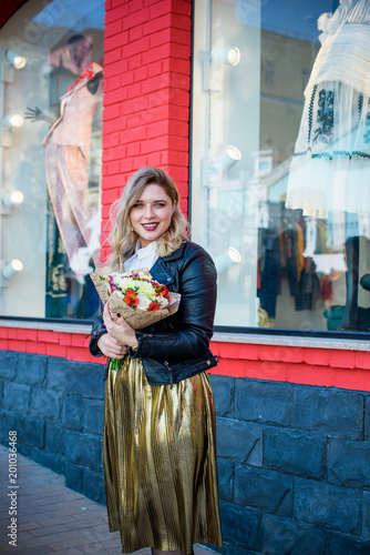 A woman of plus size, American or European appearance walks at city streets enjoying life. A young lady with excess weight, have a stylish dress. Natural beauty  photo