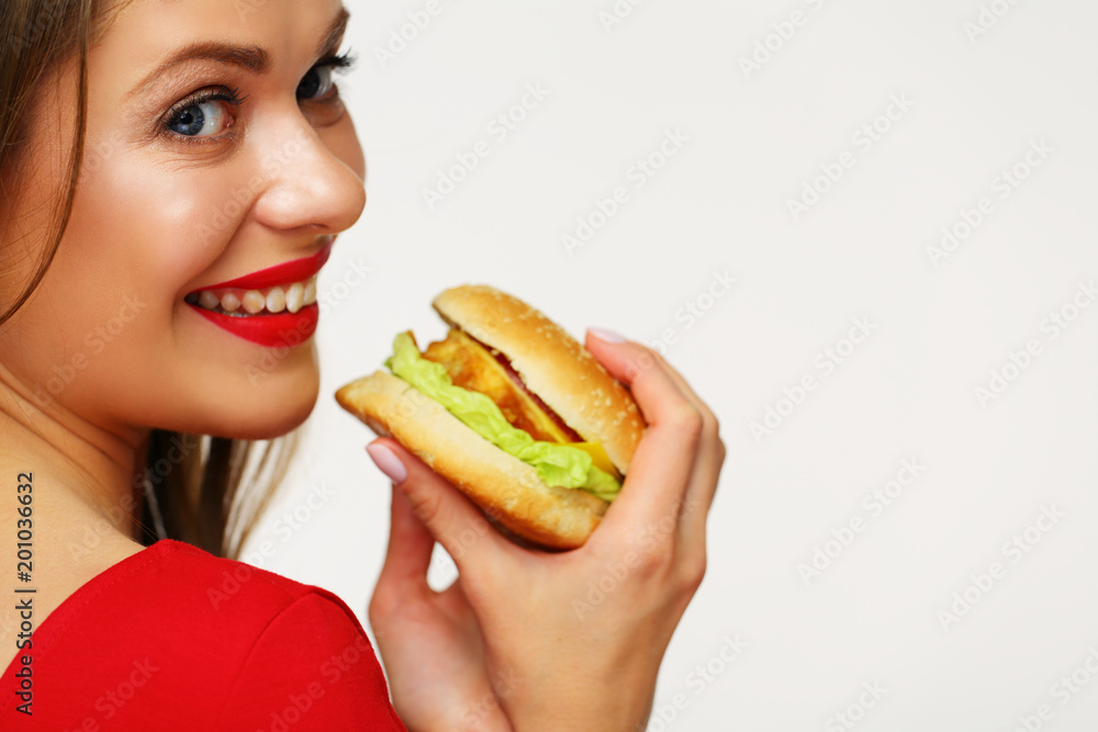 Smiling girl holding burger looks over shoulder.