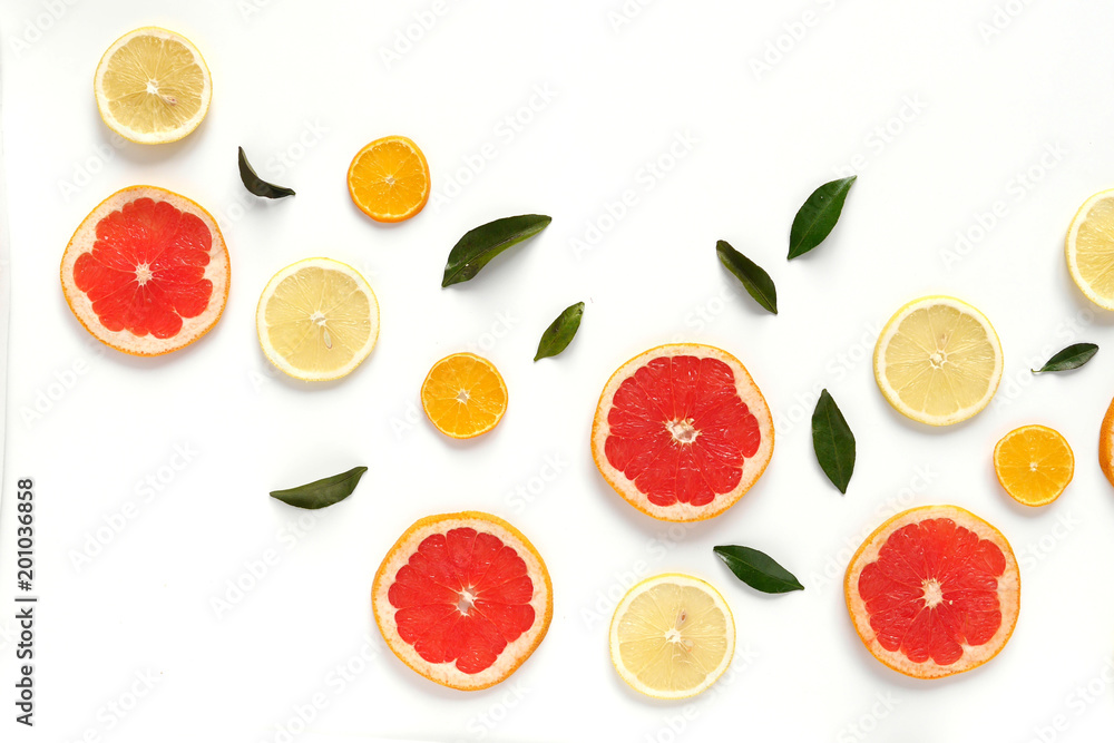Pattern of fresh fruits on a white background, top view, flat lay. Composition of green leaves and slices of citrus fruits: grapefruit, lemon, mandarin. Healthy food background, wallpaper, collage. Pattern of fresh fruits on a white background, top view, flat lay. Composition of green leaves and slices of citrus fruits: grapefruit, lemon, mandarin. Healthy food background, wallpaper, collage.