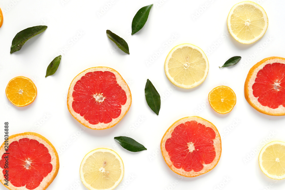 Pattern of fresh fruits on a white background, top view, flat lay. Composition of green leaves and slices of citrus fruits: grapefruit, lemon, mandarin. Healthy food background, wallpaper, collage. Pattern of fresh fruits on a white background, top view, flat lay. Composition of green leaves and slices of citrus fruits: grapefruit, lemon, mandarin. Healthy food background, wallpaper, collage.