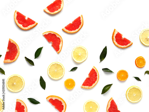 Fototapeta Naklejka Na Ścianę i Meble -  Pattern of fresh fruits on a white background, top view, flat lay.   Composition of green leaves and slices of citrus fruits: grapefruit, lemon, mandarin. Healthy food background, wallpaper, collage.