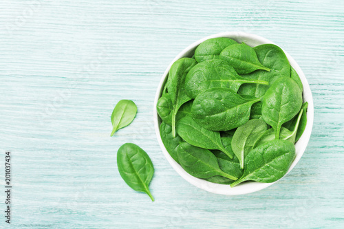 Green spinach leaves in bowl on table top view. Healthy food.