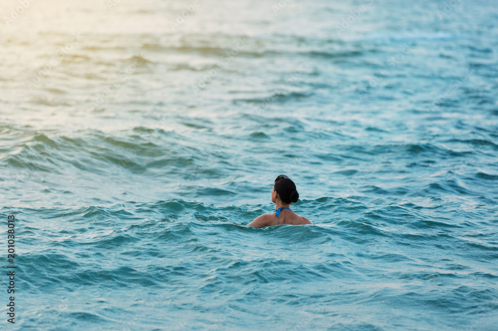 woman in the morning swims in the sea or the ocean and watches the dawn, concept life style, relaxation