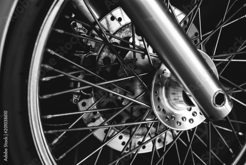 Closeup of chopper's wheel with chrome brake shoes and spokes. Black and white