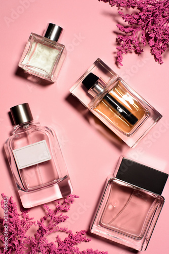 top view of bottles of perfumes with pink flowers photo