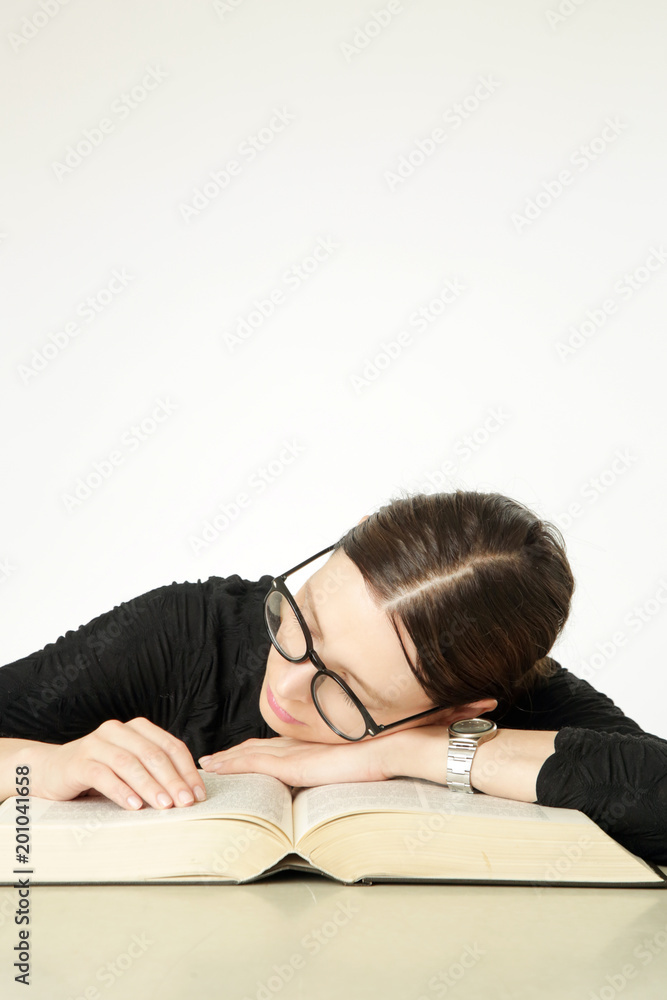 Studio portrait of young woman in front of big book on the table, don't feel like studying concept Studio portrait of young woman in front of big book on the table, don't feel like studying concept