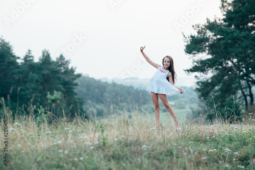 Little cutie girl in a white dress dancing in the woods