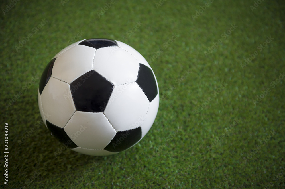 Fototapeta premium Close up view of a classic black and white football on lush green grass background