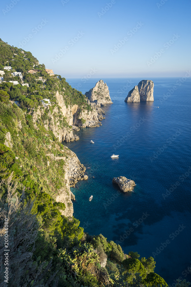 Bright scenic view of the iconic Faraglioni rocks from the cliffside trail on the Mediterranean island of Capri, Italy Bright scenic view of the iconic Faraglioni rocks from the cliffside trail on the Mediterranean island of Capri, Italy