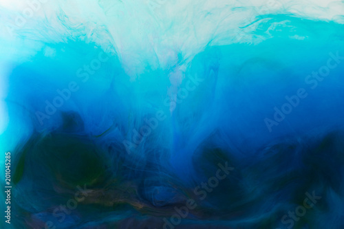 full frame image of mixing of blue, turquoise and black paints splashes in water