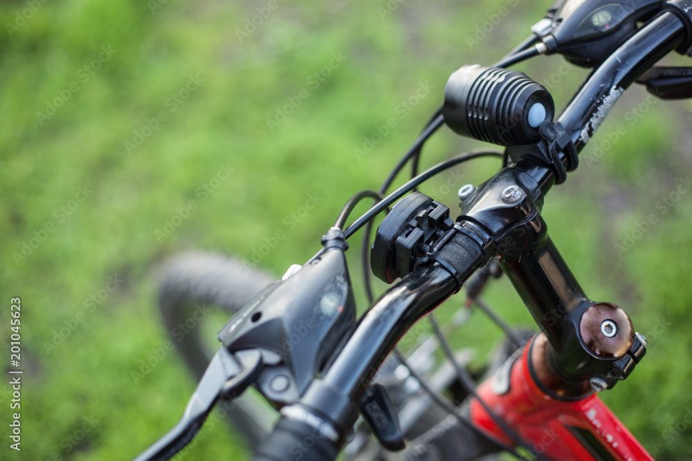 Mountain bike of red color with a black rudder on green grass Mountain bike of red color with a black rudder on green grass