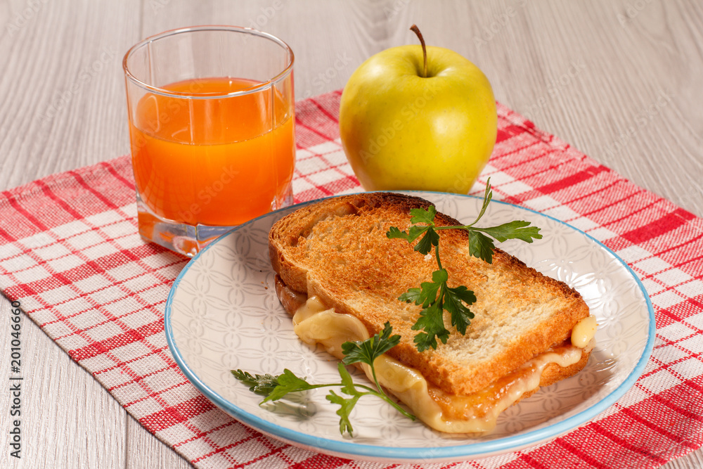 Toast with butter and cheese on white plate, apple and glass of orange juice. Toast with butter and cheese on white plate, apple and glass of orange juice.