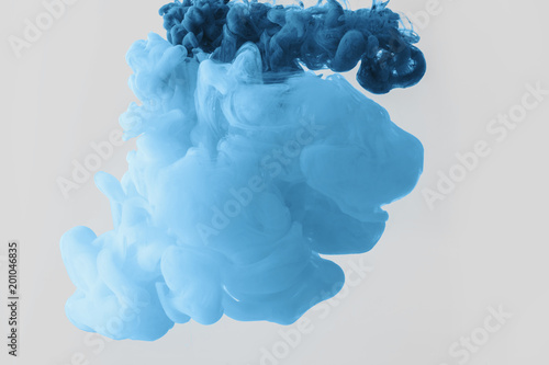 close up view of mixing of bright pale blue and blue paints splashes in water isolated on gray