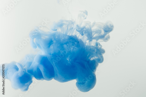 close up shot of bright blue paint splash in water isolated on gray