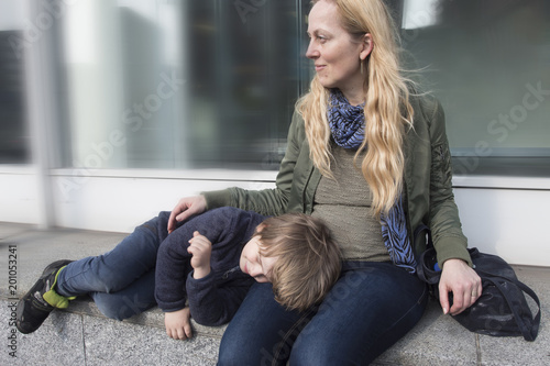 Madre cuidando a su hijo mientras descansa sobre ella. 