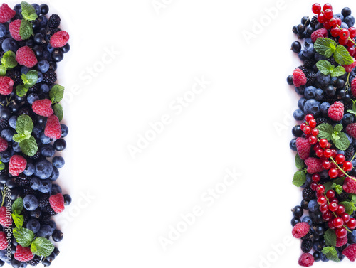 Fototapeta Naklejka Na Ścianę i Meble -  Mix berries and fruits at border of image with copy space for text. Ripe blueberries, blackberries, black currants and raspberries on white background. Top view.