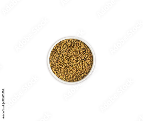 Fenugreek with seeds in a bowl. Fenugreek seeds isolated on white background. Top view.