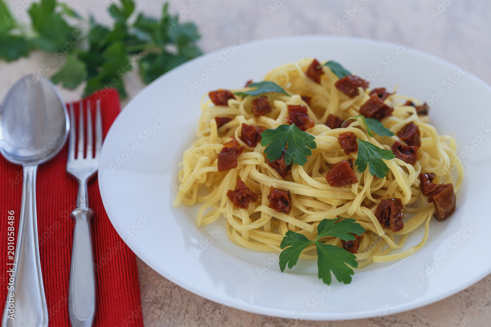 spaghetti with sun-dried red tomatoes and parsley close-up.