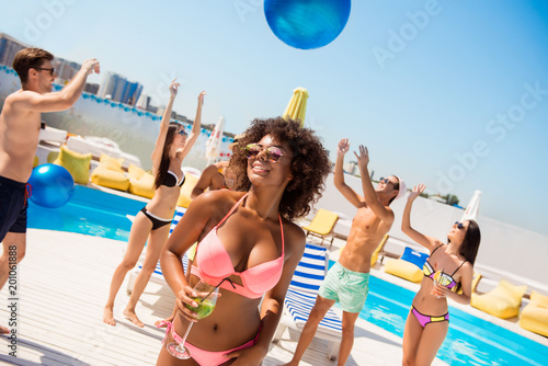 Hot chic with mohito is posing, dancing at the beach pool disco party, enjoying, chilling with friends, they play ball, with huge ribbon blue baloon, at the roof top resort with great view