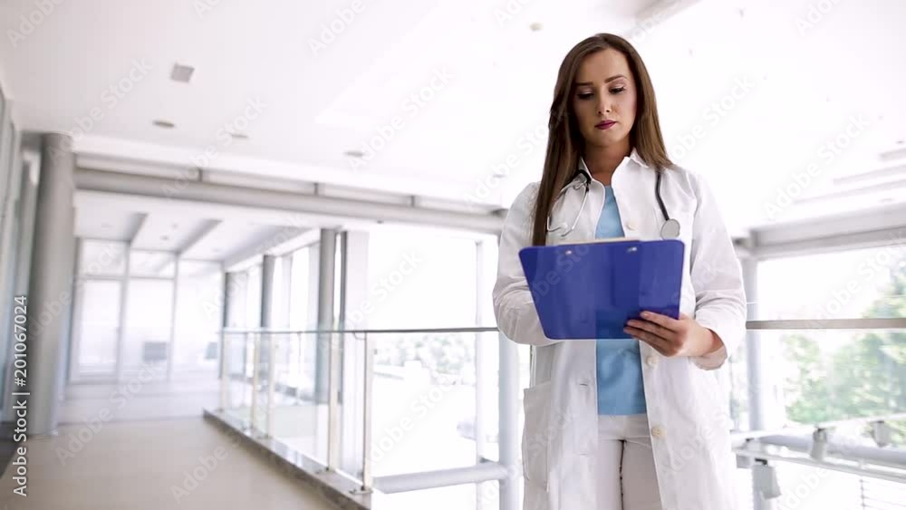 Young Female Doctor Analysing Paperboard Report Young Female Doctor Analysing Paperboard Report