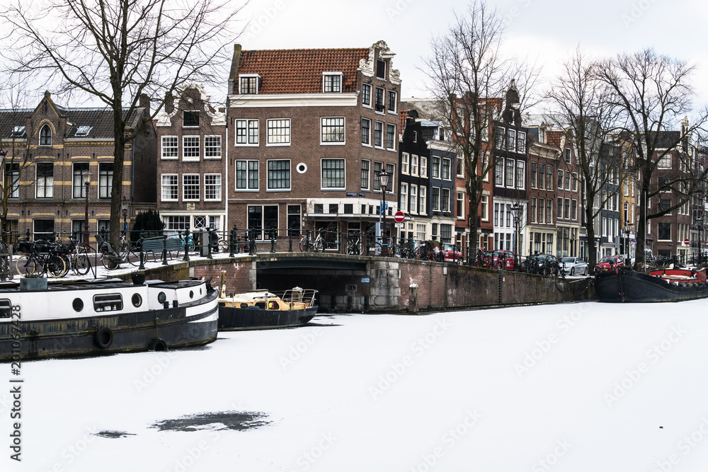 Obraz premium Stunning view of Amsterdam canals and house boat frozen with snow during the cold wave in February 2018 on a very cold winter day.