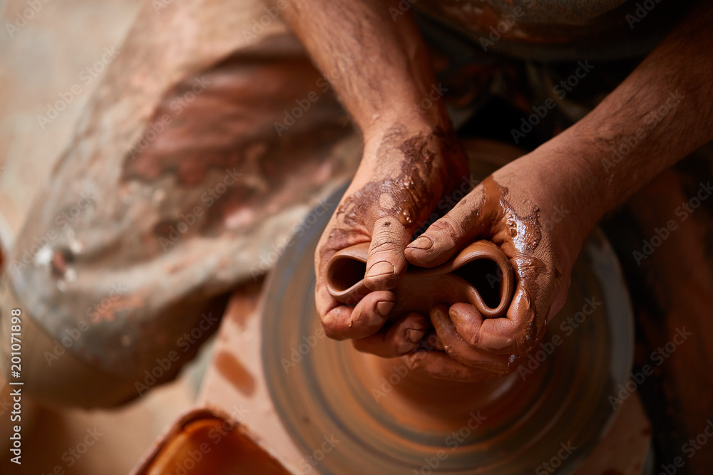 Close-up hands of a male potter in apron squizing wrong bowl from clay, selective focus Close-up hands of a male potter in apron squizing wrong bowl from clay, selective focus