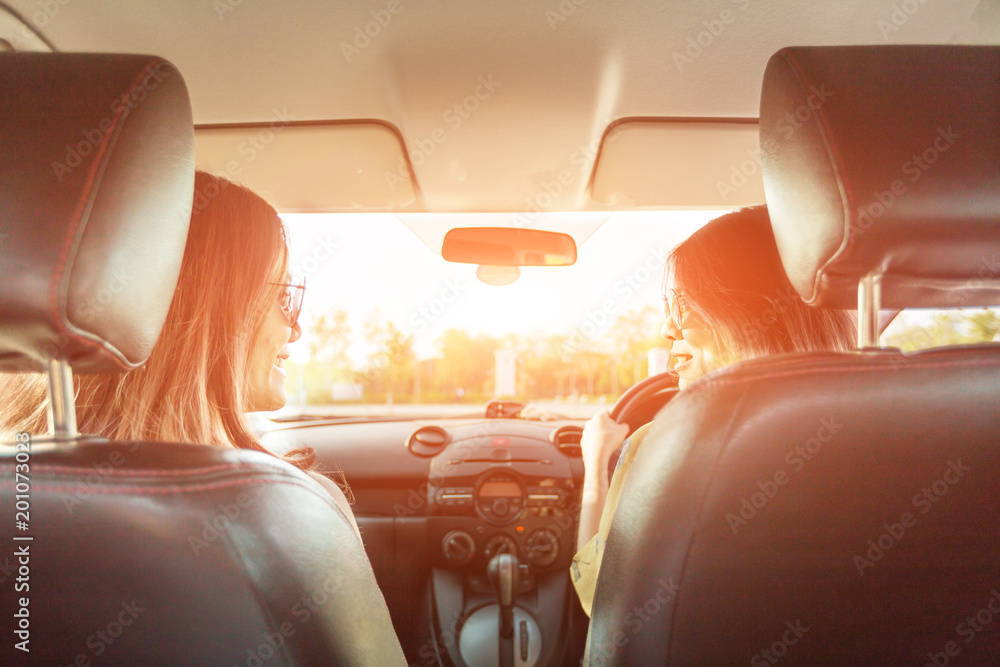 Fototapeta premium Enjoying woman and friend driving in red car summer vacation, holidays, travel, road trip and people concept .