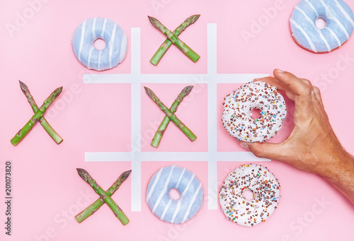 Playing in tik tak toe game with donuts and asparagus. Health nutrition concept image