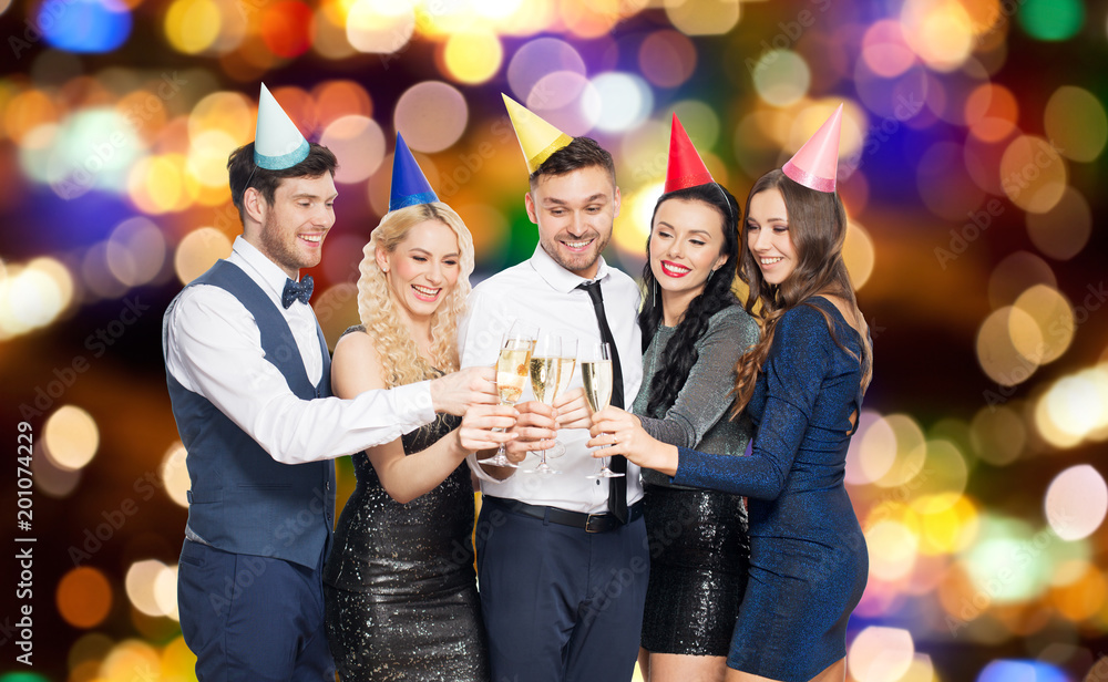 celebration and holidays concept - happy friends clinking champagne glasses at birthday party over festive lights background