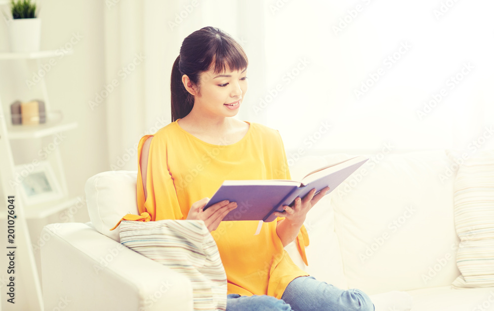 leisure, literature and people concept - smiling young asian woman reading book at home leisure, literature and people concept - smiling young asian woman reading book at home