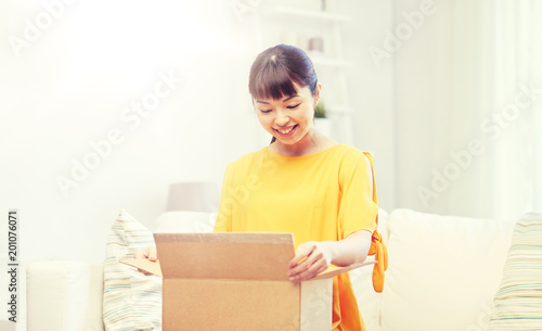 people, delivery, commerce, shipping and shopping concept - happy asian young woman with cardboard parcel box at home
